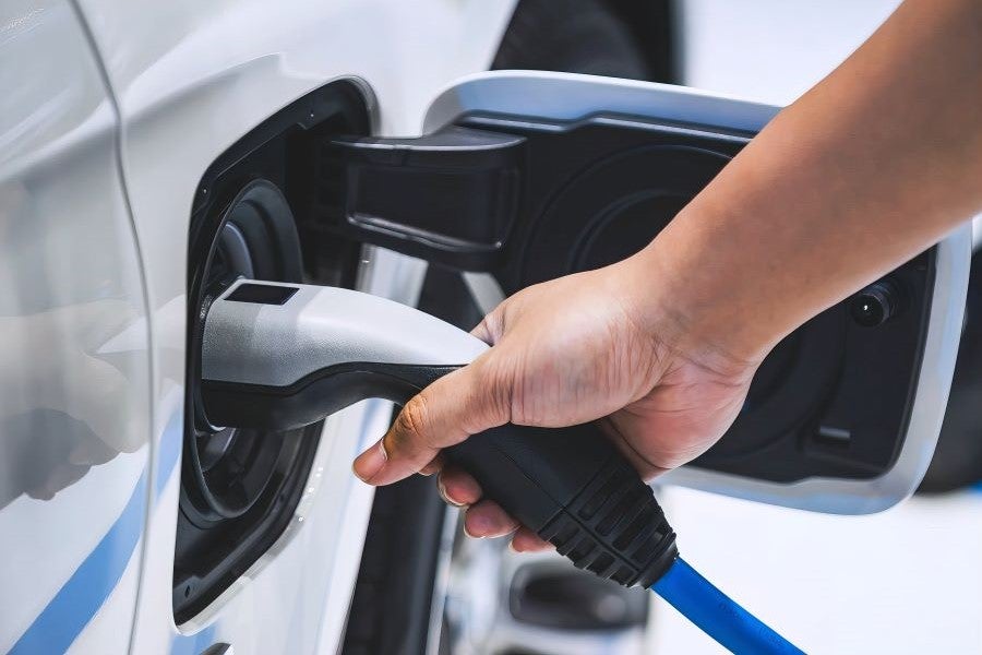 A man plugging in an EV and monitoring on phone